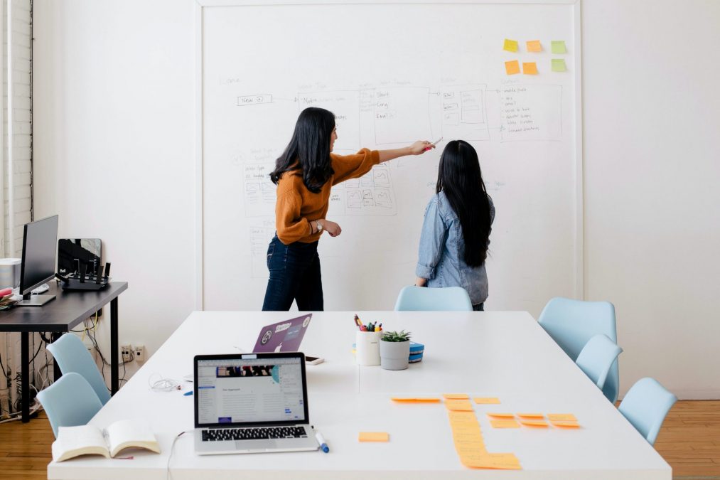 finance stream employees pointing to web designs on a whiteboard